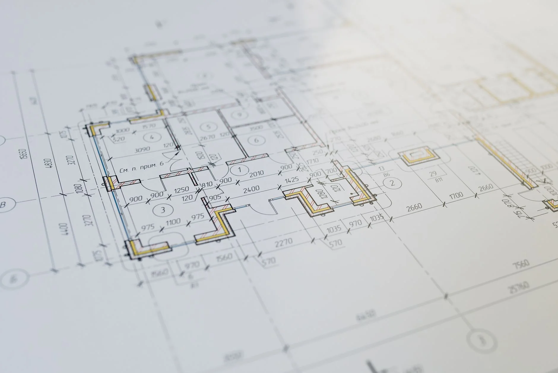 An architecture blueprint laid flat on a wooden table with pencil and metal ruler ready for annotation