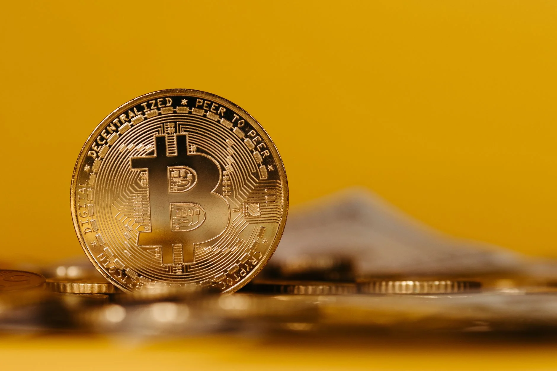 A physical gold-colored Bitcoin coin photographed in close macro detail