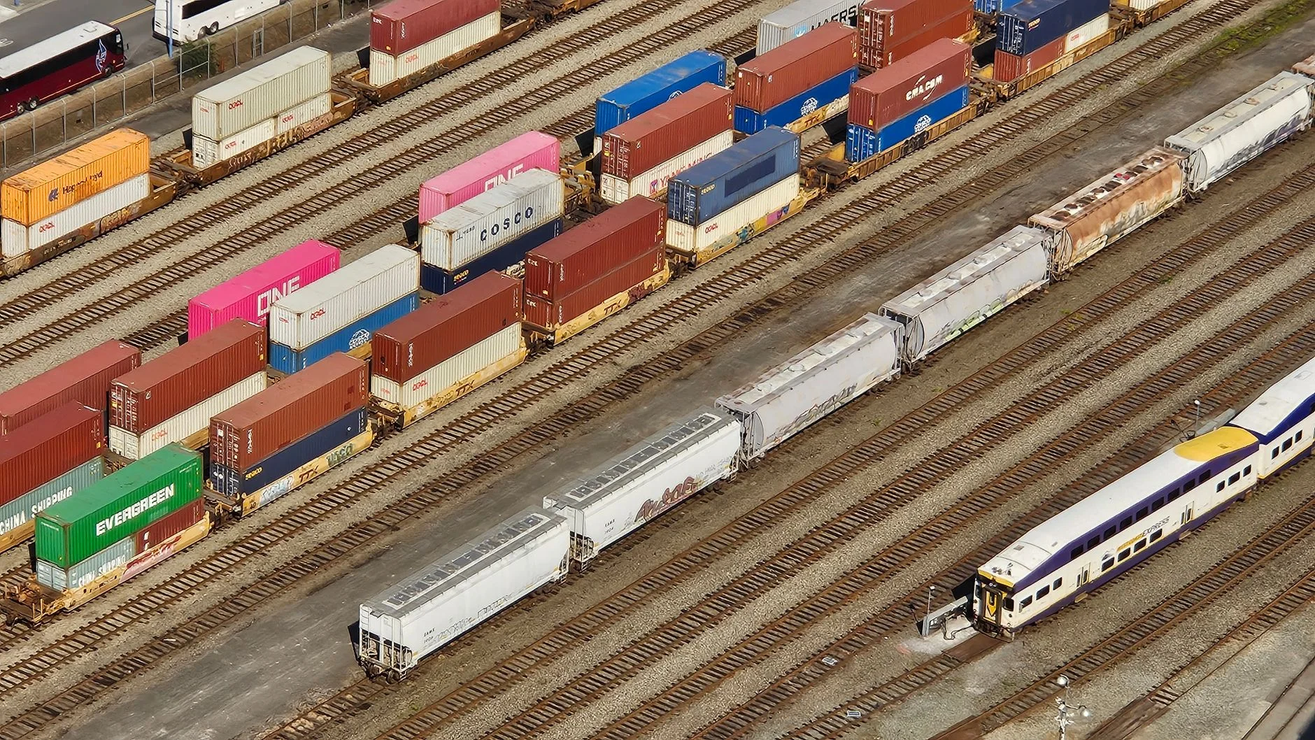 An aerial view of a freight container yard with shipping containers arranged in rows under daylight