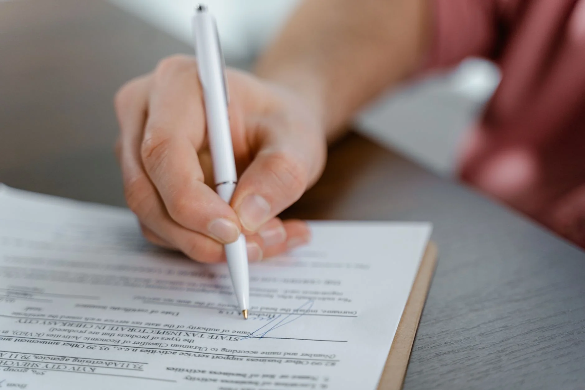 A stack of signed contract pages on a desk with a pen resting on top