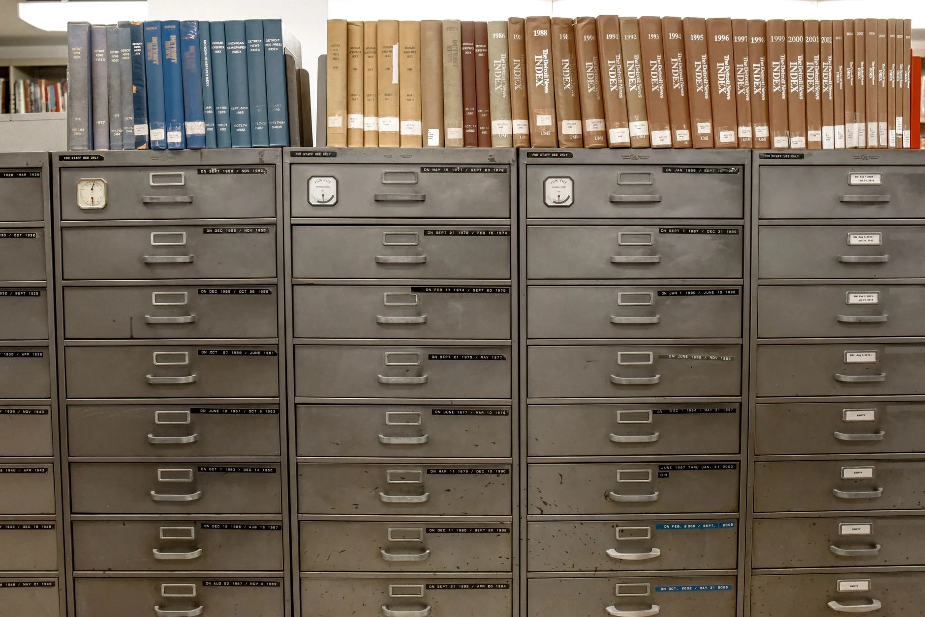 A close-up of a wooden library card catalog with drawer labels