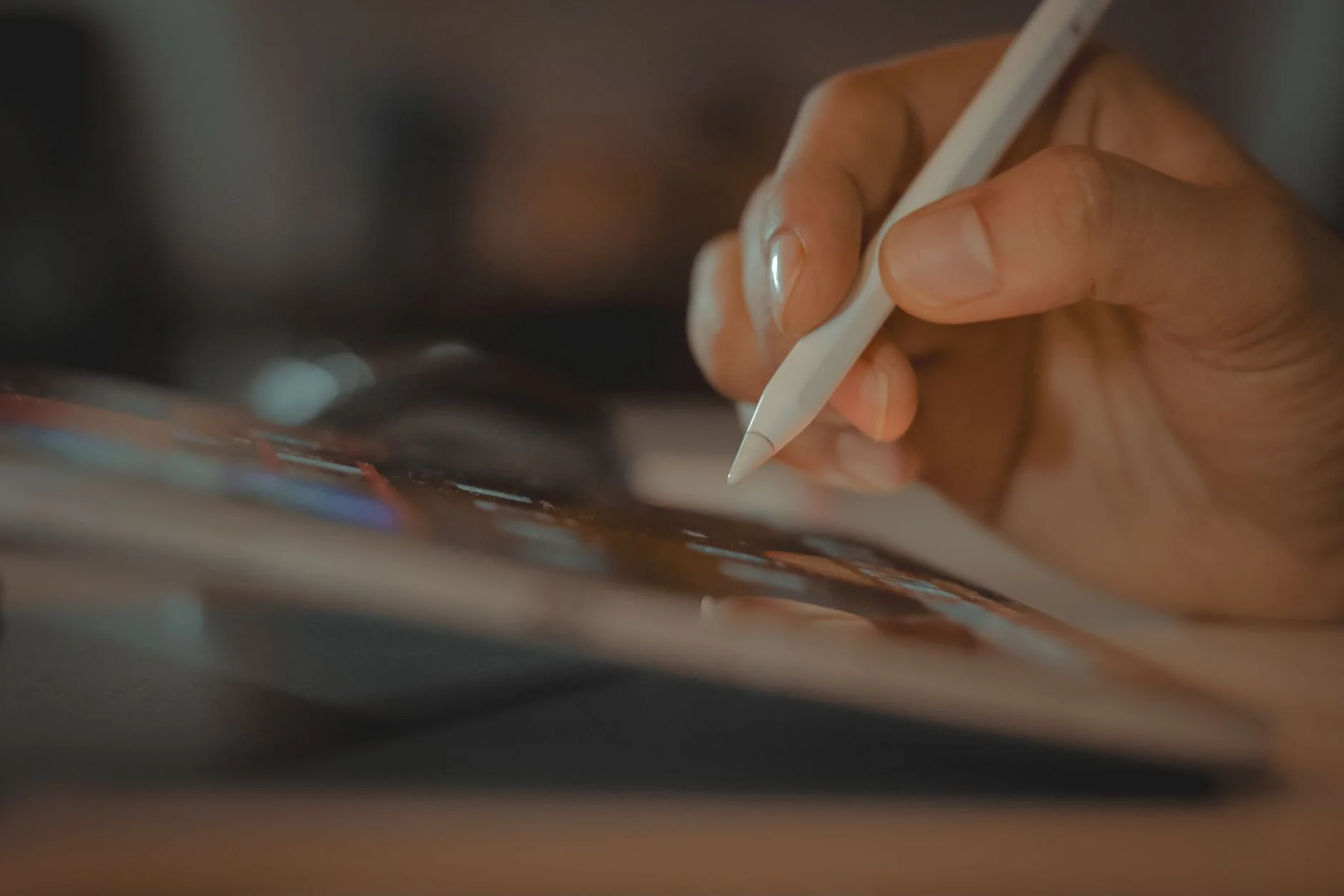 A hand holding a stylus over a tablet screen showing a interface layout